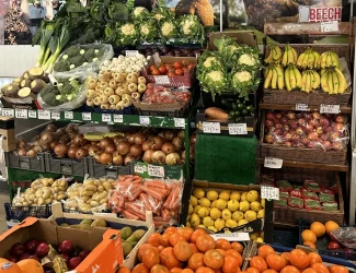 An isle of fresh fruit and vegetables including bananas, oranges, carrots and onions